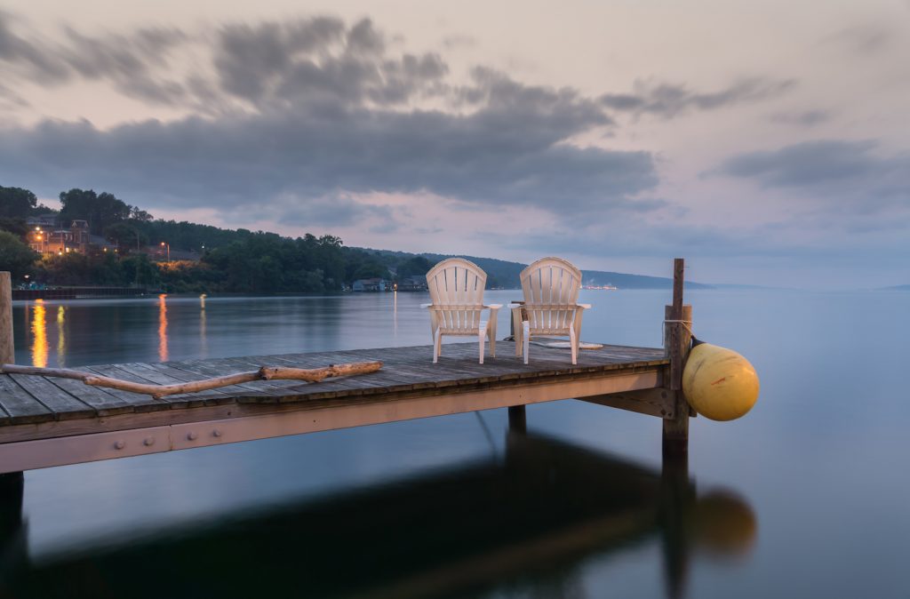 Two chairs sitting on a jetty at dusk, form a tranquil and idyllic scene at Lake Seneca, a popular vacation destination and located in the famous Finger Lakes region in New YorkState.